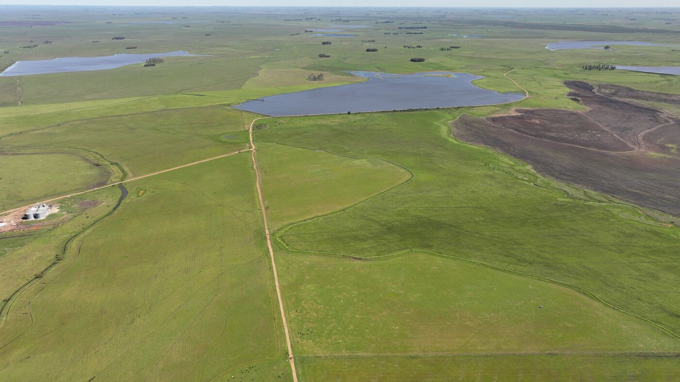 Vista aérea com barragem, lavoura preparada e campo